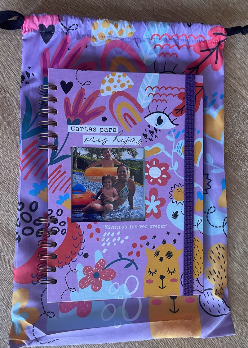 Cuaderno Cartas para mis hijas: agenda argollada de tapa lila con ilustraciones de flores, gatos y corazones, ventana para la foto, elástico morado y su bolsa de tela a juego.